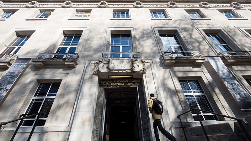 A students walking up the steps of the LSHTM Keppel Street entrance, viewed from below.