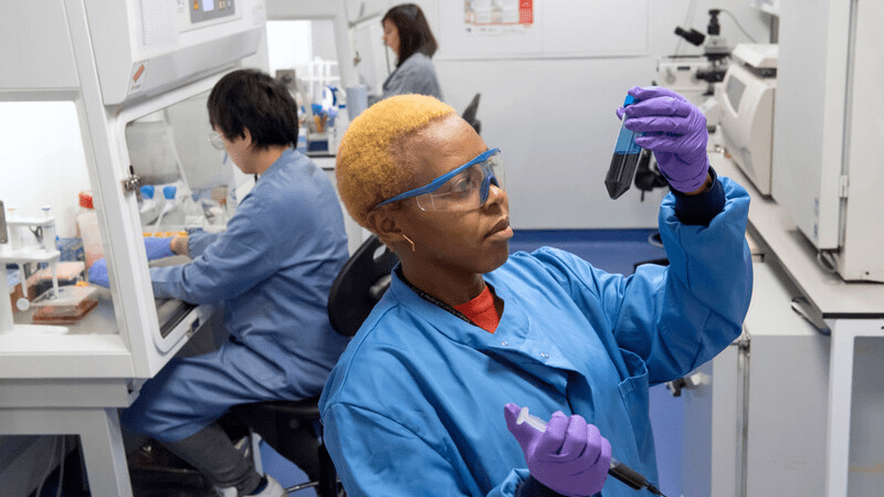 Three researchers in a lab, carrying out various tasks.
